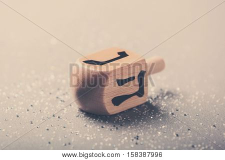 Wooden dreidel for Hanukkah on light background