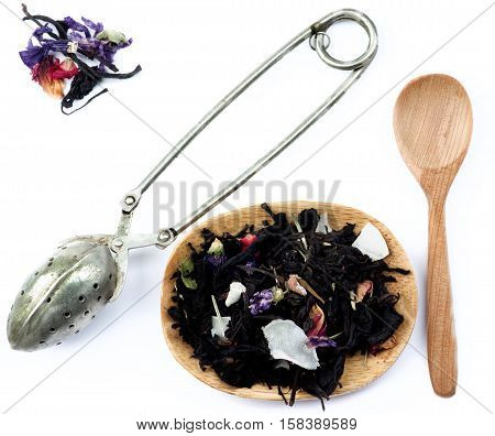 Tea Leafs Concept with Vintage Brewing Spoon Heap of Tea with Fruits and Flowers Leafs in Wooden Plate and Wooden Spoon closeup on White background