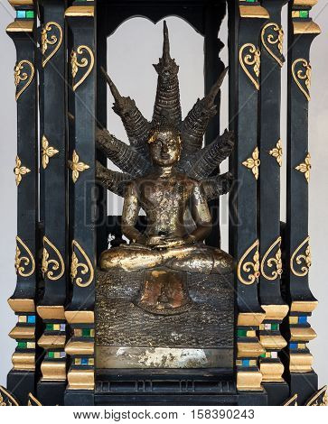 Brass Buddha statue with seven head dargon in the small wooden altar.