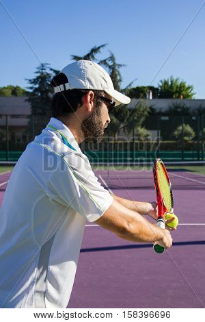 Professional tennis player is doing a kick tennis on a tennis court on a sunny summer morning. He is dressed in sportswear.