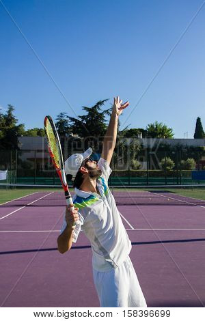 Professional tennis player is doing a kick tennis on a tennis court on a sunny summer morning. He is dressed in sportswear.