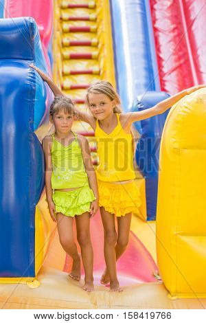 Two Children Stand At The Entrance Of A Large Inflatable Trampoline