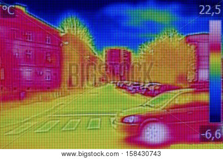 Infrared thermovision image showing lack of thermal insulation on Residential building and cars on the street