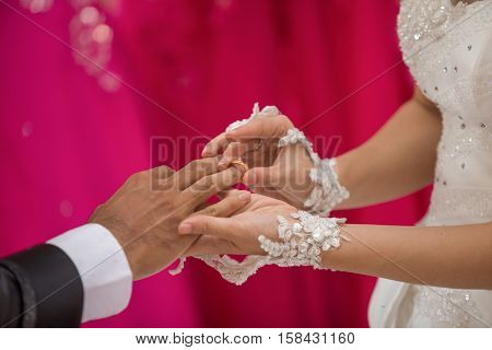 The bride was giving a wedding ring to the groom at the wedding ceremony.