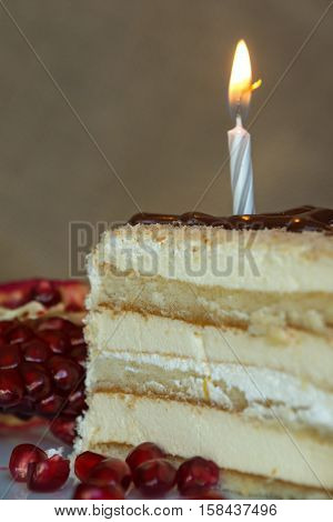 Portion homemade cream cake with candle and pomegranate seeds and chocolate spread. Macro view.