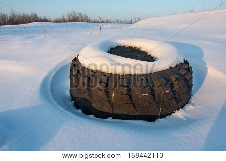 old lost tyre on winter meadow
