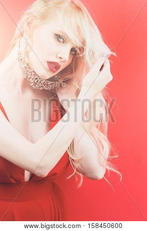 young pretty sexy woman or girl with cute face and long blond hair has red lipstick on lips in dress holds jewelry crown with diamonds in studio