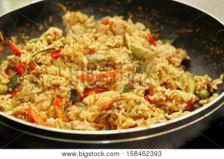 Hot cooking home made,Fried jasmine rice in green curry with meat (shrimp,squid,chicken liver and chicken hearts) topped halve green lemon ,sliced tomato, cucumber,correspondents and basil leaf. Selective focus