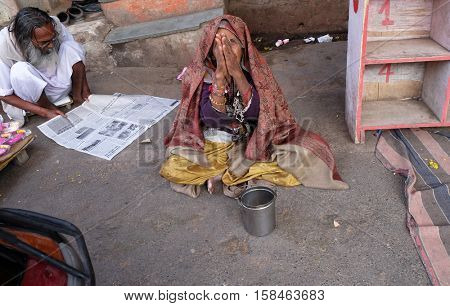 PUSHKAR, INDIA - FEBRUARY 17: Unidentified old indian beggar waits for alms on a street on the ghat along the sacred Sarovar lake in Pushkar, India on February 17, 2016.