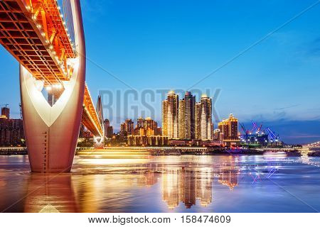 cityscape and skyline of downtown near water of chongqing at night