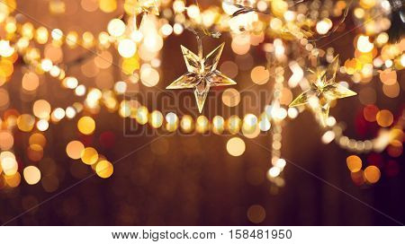 Christmas and New Year glowing Background with Holiday Decoration garland, tinsel and stars. Abstract Blurred Bokeh Holiday Backdrop. Blinking Garland. Christmas Tree Lights Twinkling