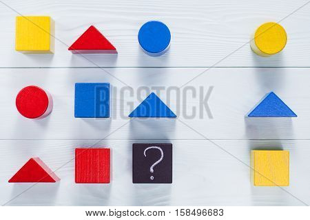 IQ test. Choose correct answer. Logical tasks composed of geometric wooden shapes. Children's educational logical task flat lay.