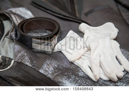 Wedding tie, belt, and gloves lying on a vest and suit