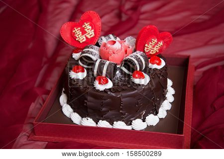 Black forest cake whole pastry decorated with whipped cream, red cherry, double happiness, and shuang xi love heart