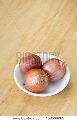 Shallots in white cup on wooden cutting board