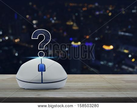 Wireless computer mouse with question mark sign icon on wooden table over blur light city tower Customer support concept
