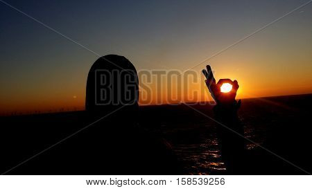 A siluet before sundown. The sun is closed in hand.