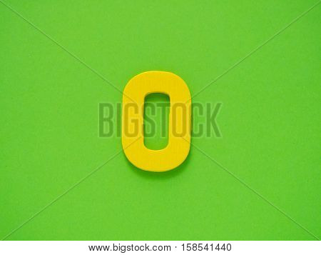 Capital letter O. Yellow letter O from wood on green background. Alphabet vowel.