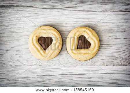 Two jam biscuits in the shape of heart on the wooden background. Food theme. Symbolic sweets. Valentine's Day.