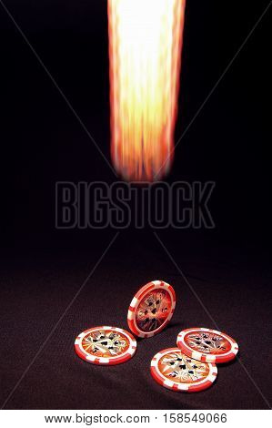 Luminous falling poker chip on black background and heap of red poker chips