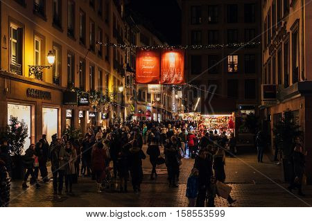 STRASBOURG FRANCE - NOV 28 2015: People walking under immense crystal chandeliers from Baccarat on the rue des Hallebardes in Strasbourg France with immense light illuminations Alsace