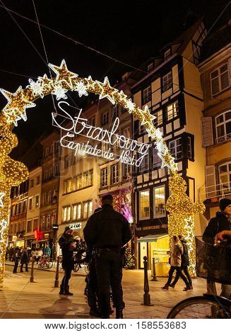 STRASBOURG FRANCE - NOV 28 2015: Police officers surveilling the entrance gate with neon Christmas decorations of the Christmas Market in Strasbourg with high grade security after Paris attacks