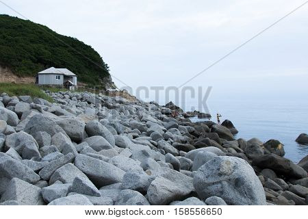 Rocky shore. Tent on the beach. The girl catches a fish. The machine on the beach. Relax on the beach. Japanese Sea.