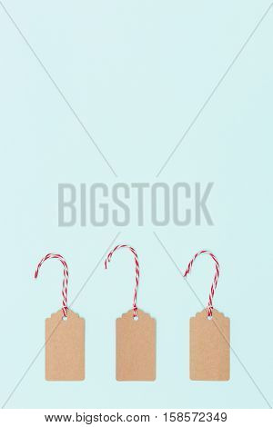 christmas tags in plain cardboard with red string and white string on light blue background. Merry Christmas. Holiday season concept