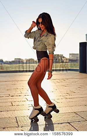 Full length of happy young woman roller skating. Fashion, extreme, youth and people concept - pretty stylish hipster girl rollerblading in the city park, cool roller girl outdoors.