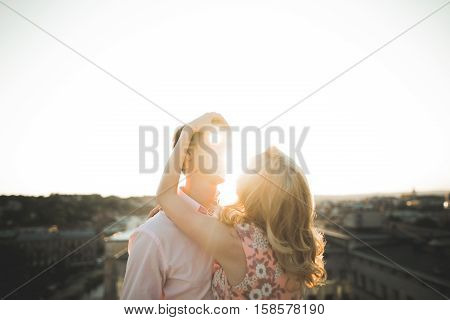 Close up portrait of happy smiling couple in love posing on roof with big balls. Landscape on city.