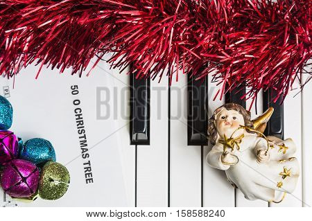 Christmas music concept. Printed music on the pianto with jingle bells angel and spangle.