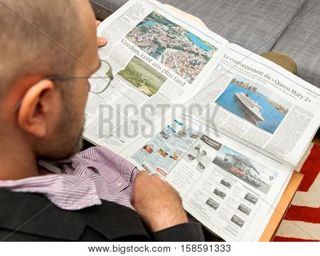 PARIS FRANCE - NOV 12 2016: Man reading Le Figaro et Vous lifestyle French newspaper - article about Queen Mary 2 the new transatlantic ocean liner