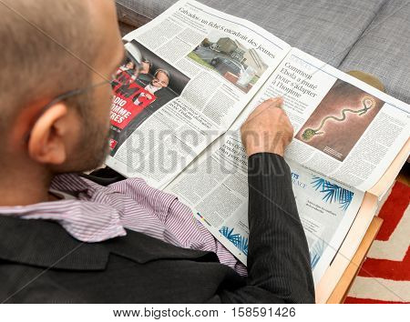 PARIS FRANCE - NOV 12 2016: Man reading Le Figaro French newspaper about the Ebola spread and its treatment