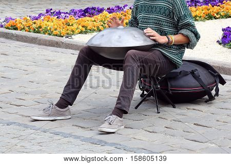 the man on the street plays a percussion instrument hang