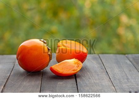 Ripe persimmon kaki fruits on wooden old table in garden. Diospyros kaki.