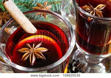 close up of two glasses of mulled wine with christmas wooden background