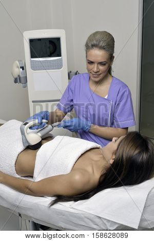 Young beautiful woman gets professional body shape treatment in a beauty clinic