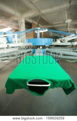 Green t-shirt silk screen printing machine, look of the mock up clothing before high quality printing process. Vertical image
