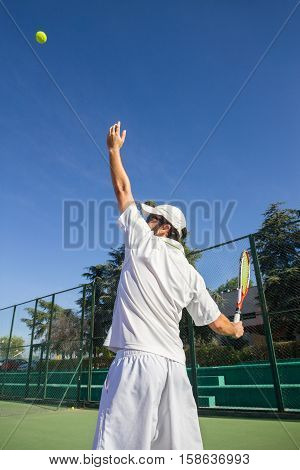 Professional tennis player is doing a kick tennis on a tennis court on a sunny summer morning. He is dressed in sportswear.