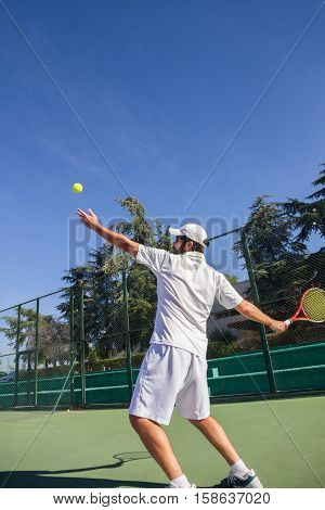 Professional tennis player is doing a kick tennis on a tennis court on a sunny summer morning. He is dressed in sportswear.