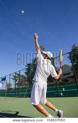 Professional tennis player is doing a kick tennis on a tennis court on a sunny summer morning. He is dressed in sportswear.