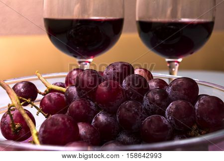 wine in the wine glass grape in the vase on the table