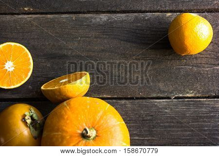 n a wooden background pumpkin persimmon oranges and tangerines. orange fruits