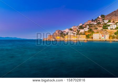Hydra island in a summer evening in Greece. Beautiful landscape with sea and island at sunset lit with purple light.