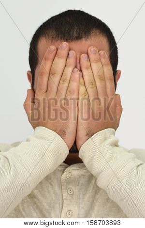 A picture showing a man covering his face with his palms