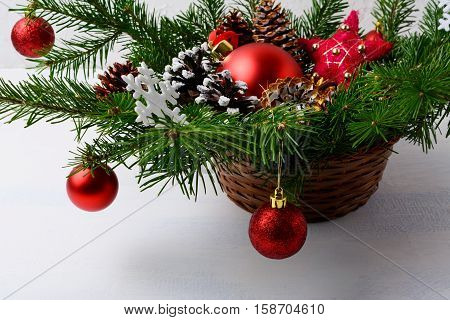 Christmas red ornaments and snowy decorated pine cone table centerpiece. Christmas background with arrangement in wicker basket.