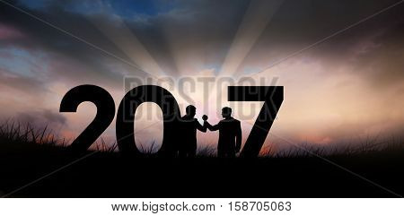 Silhouettes shaking hands against blue sky over grass