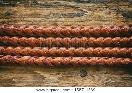 detail texture natural brown leather belt braided pigtail on wooden old table