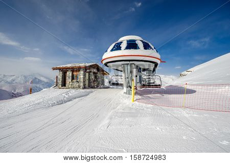 Ski lift station in mountains at winter. Alpine winter mountain landscape. French Alps covered with snow in sunny day. Val-d'Isere, Alps, France