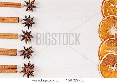Christmas food - mulled wine background. Decorative frame of spice ingredients - anise stars cinnamon dried oranges and wine on wood white surface. Top view.